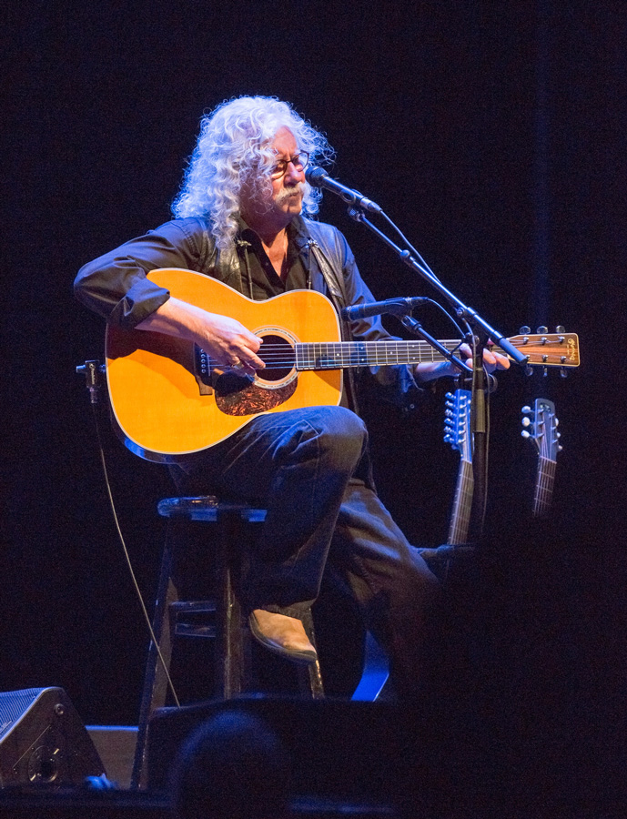 Color photograph of Arlo Guthrie playing acoustic guitar at The Carolina Theatre by Willa Stein